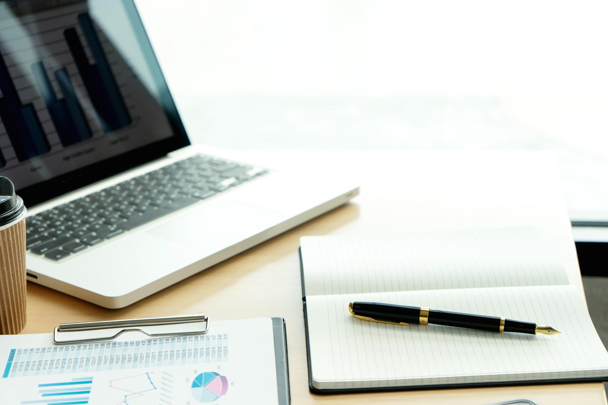 Documents, pen and laptop on desk